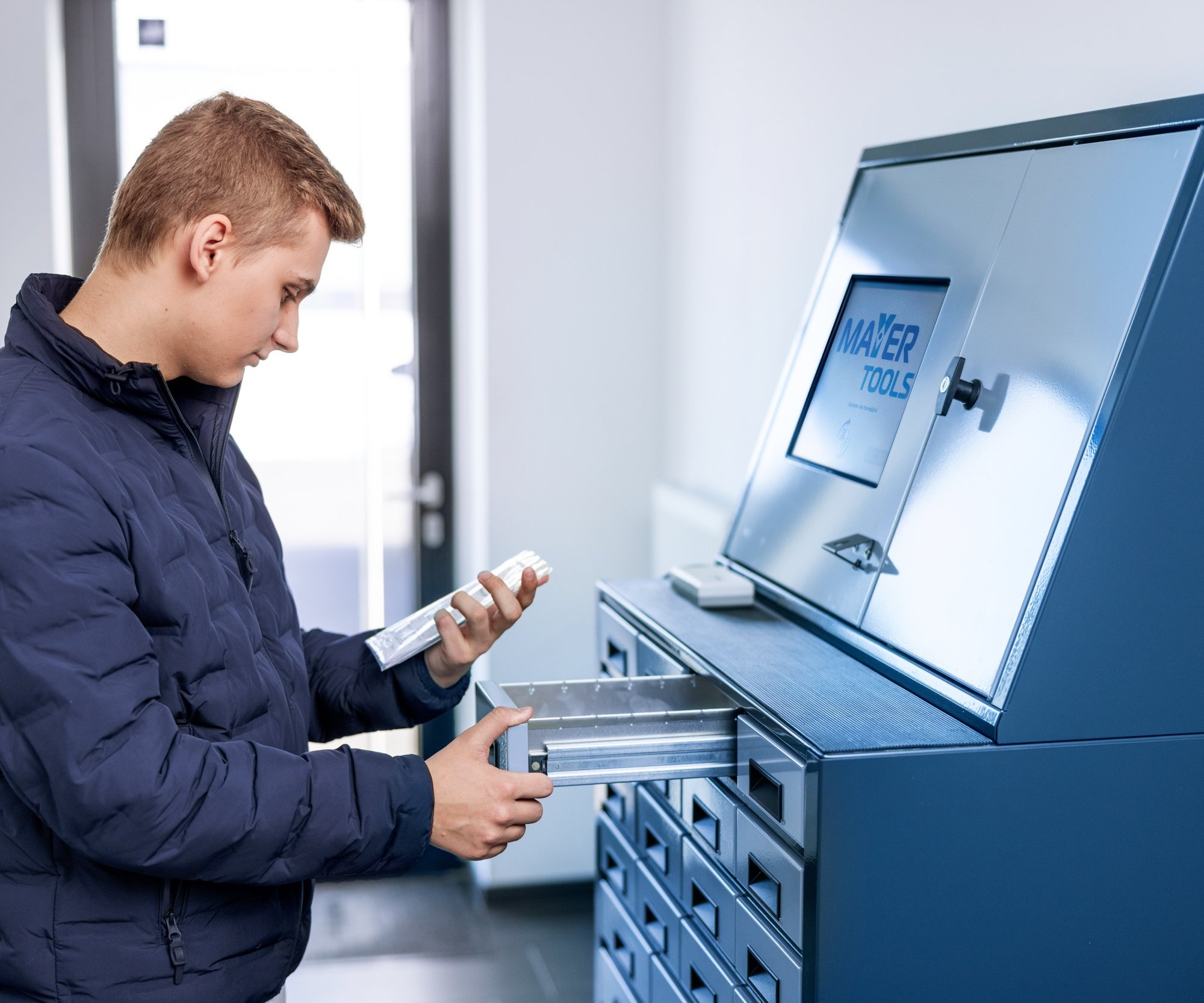 Ein Mann entnimmt eine Werkzeugbestellung aus einem Fach im Abholraum.