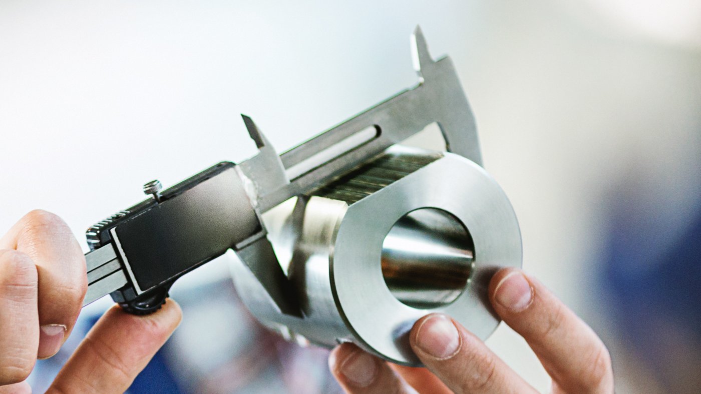 Ein Mann vermisst ein Bauteil aus Edelstahl mit einer Schieblehre