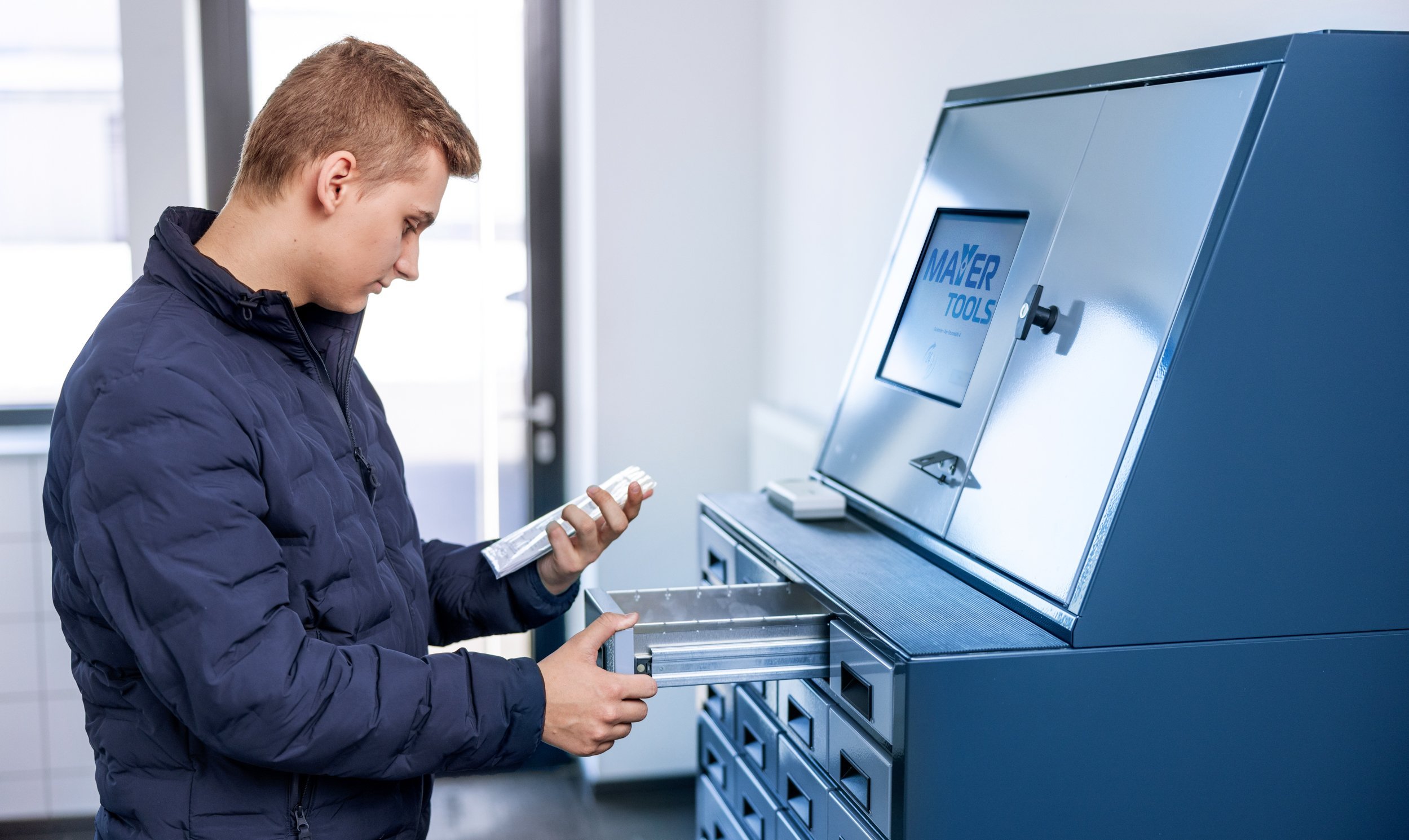 Ein Mann entnimmt eine Werkzeugbestellung aus einem Fach im Abholraum.