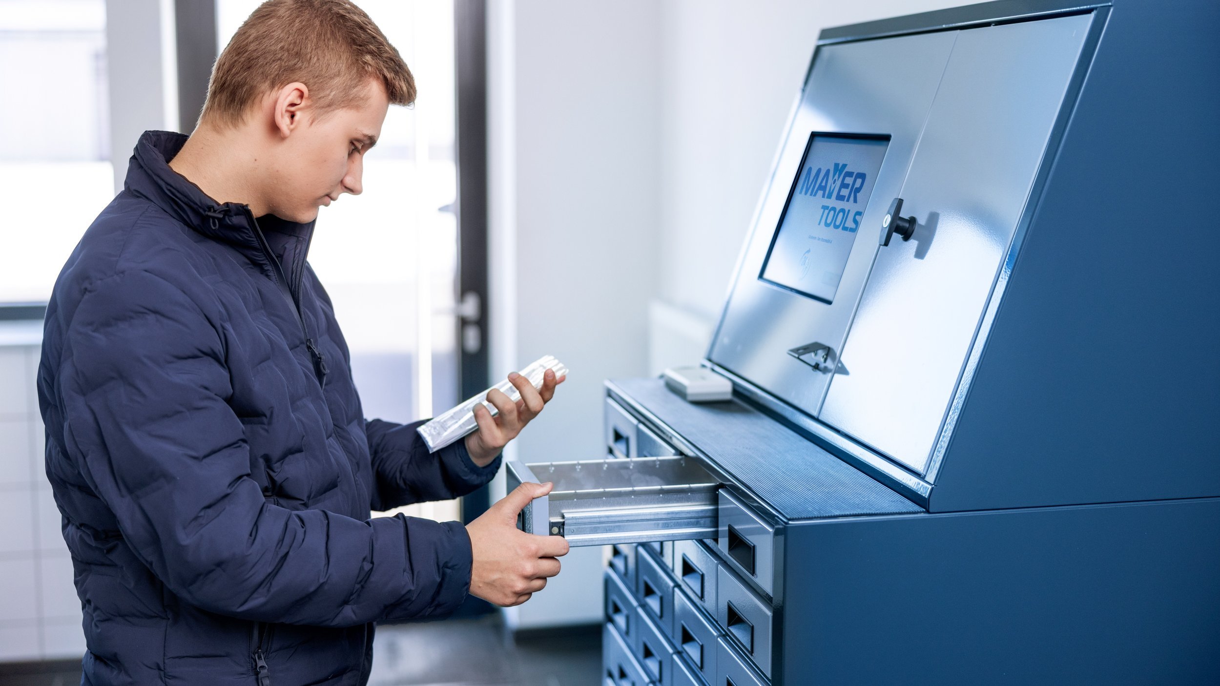 Ein Mann entnimmt eine Werkzeugbestellung aus einem Fach im Abholraum.